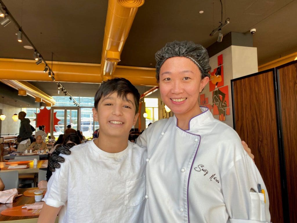 A young boy poses with a hotel chef after a cooking class.