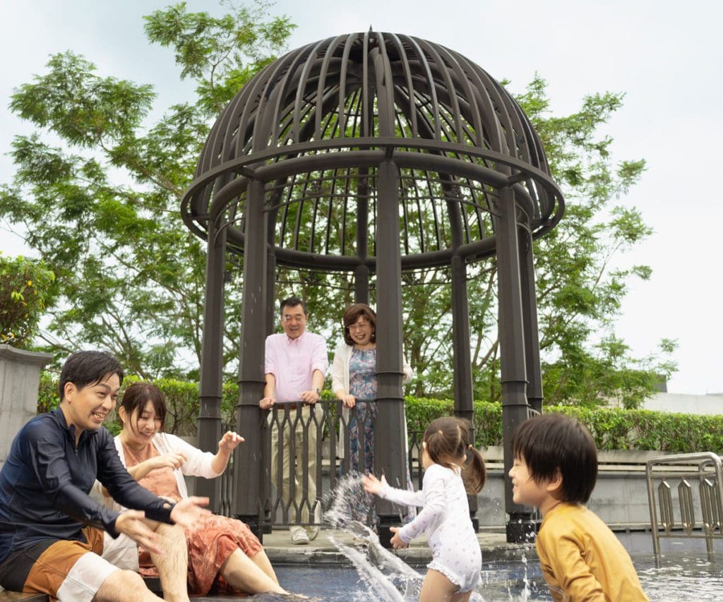 A multi-generational family plays in the outdoor pool at Grand Park City Hall.