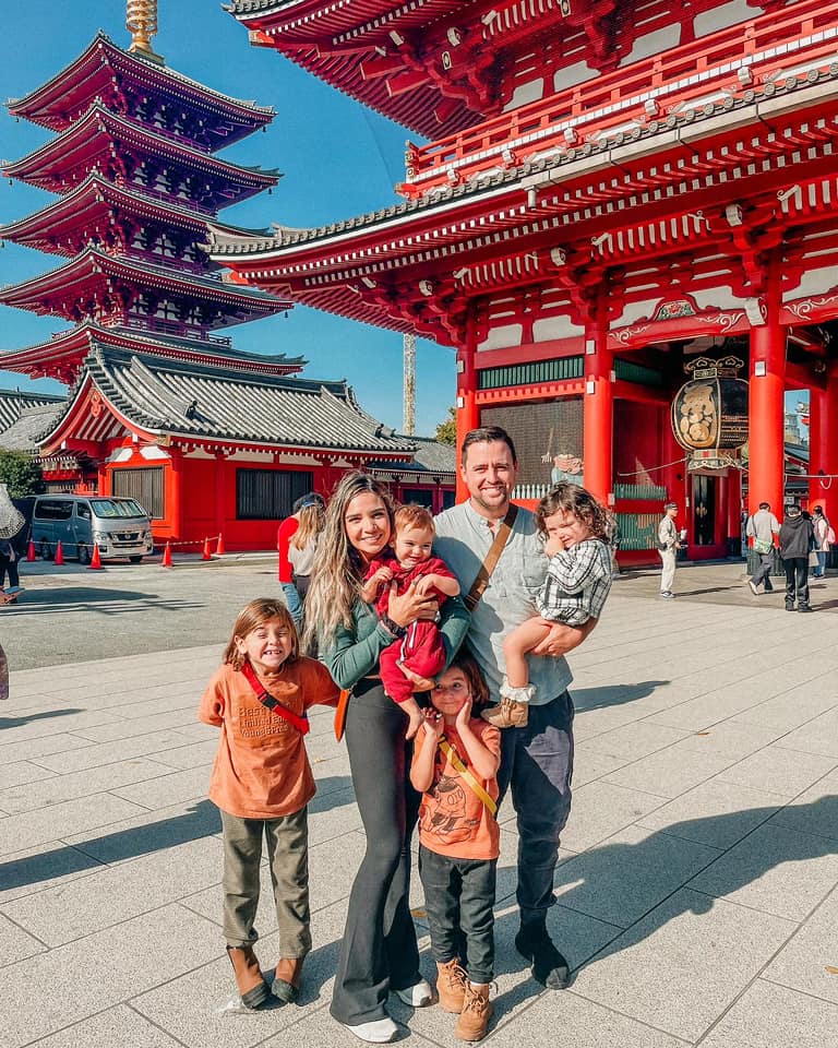A family of five stands together in front of a temple in Tokyo.