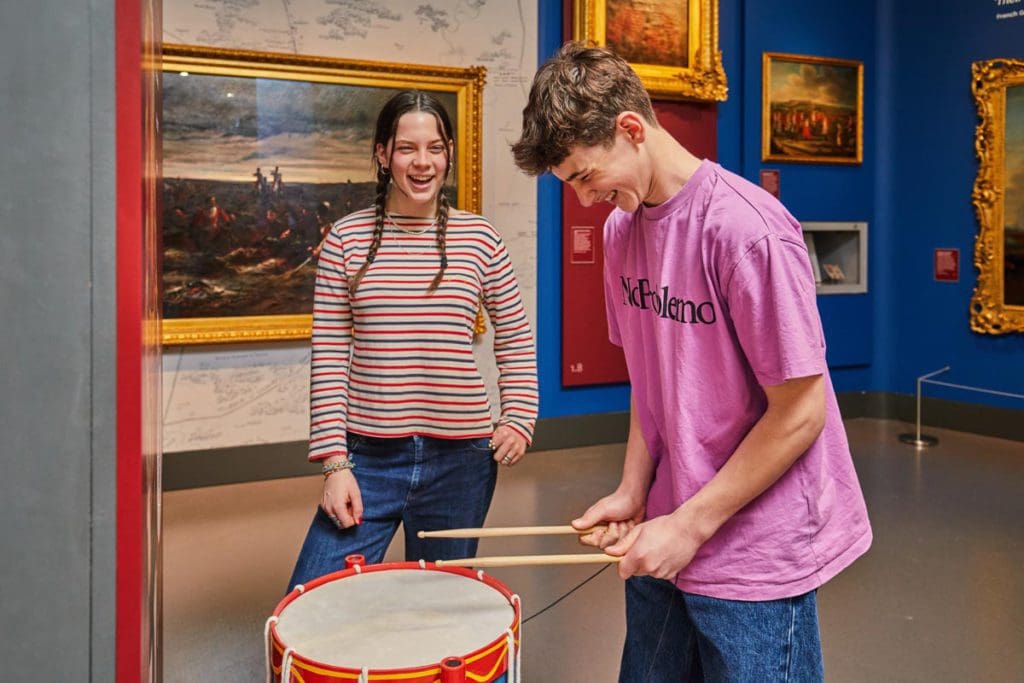 Two teens play a drum at National Army Museum, one of the best museums in London for kids.