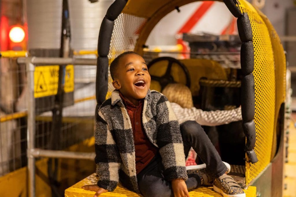A young boy enjoys the Mail Rail at The Postal Museum, one of the best museums in London for kids.