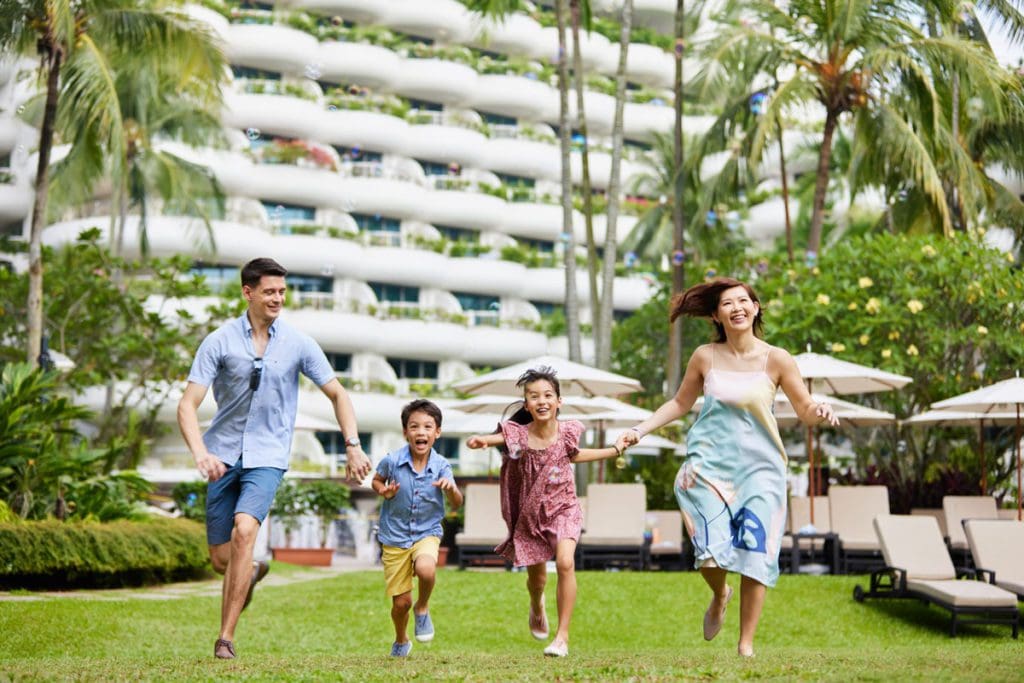 A family walks across the lush lawn of Shangri-La Singapore, one of the best hotels in Singapore with kids.