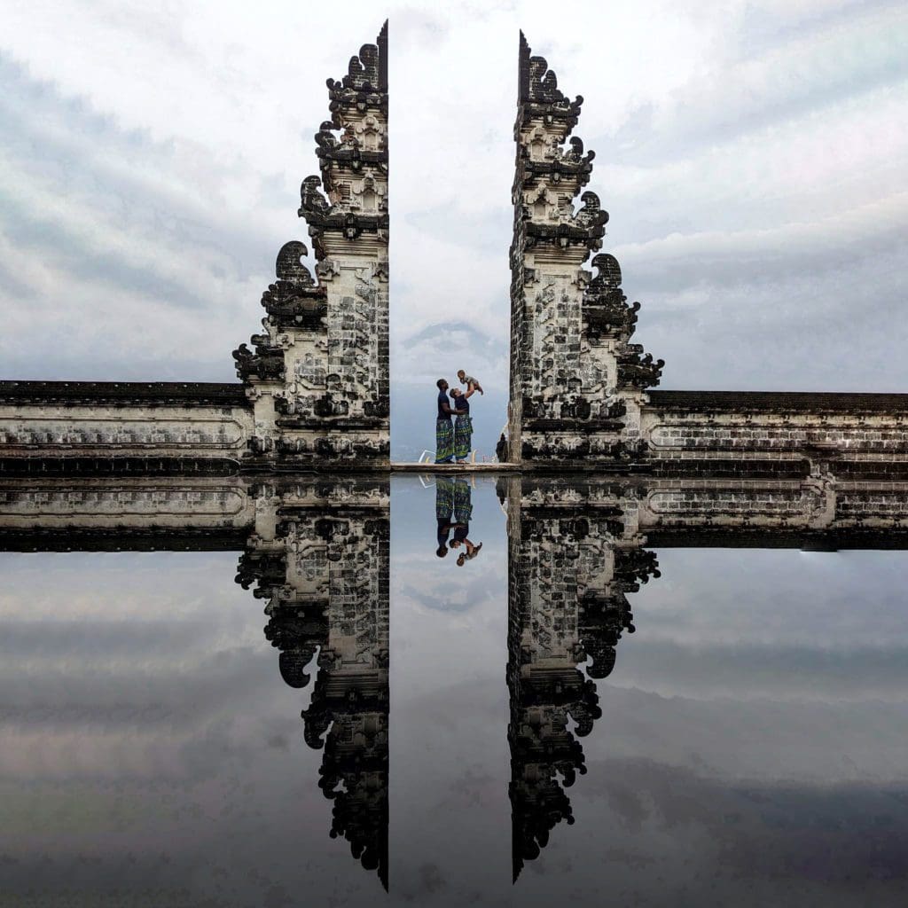 A family of three stands at the iconic gates of Bali.