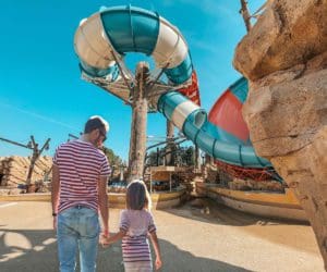 A dad and his young daughter walk up to a waterslide at Yas Island.
