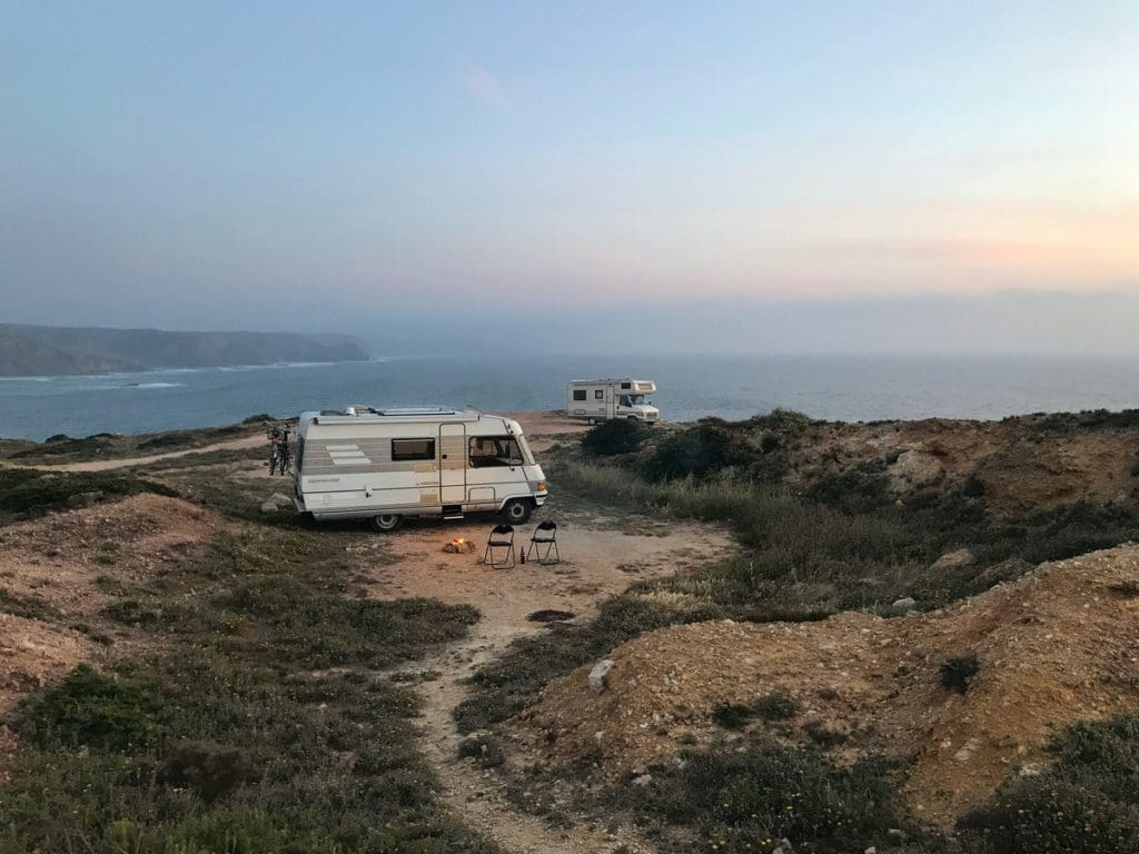 A motorhome is parked on the edge of a cliff overlooking the ocean.