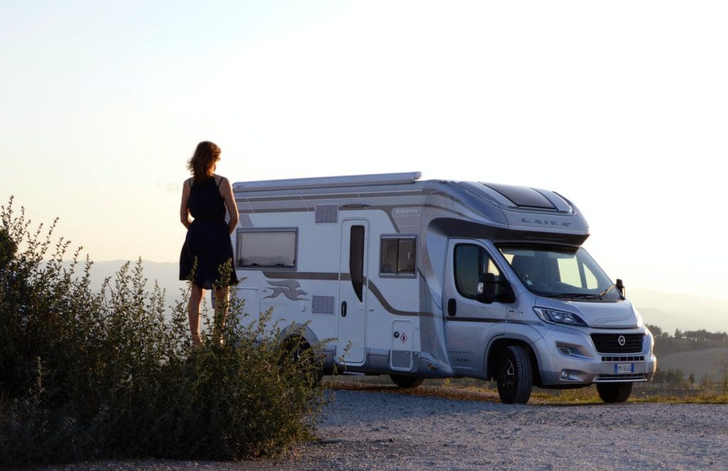 A woman standing outside of a motorhome.