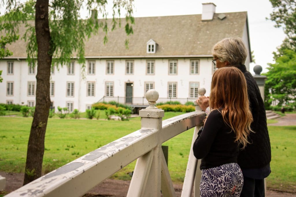 A young girl and her grandmother stand on an old wooden bridge at Domaine de Maizerets.