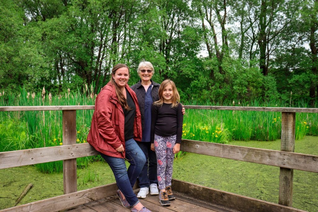 Two women and a young girl stand together with a beautiful woods around them at Domaine de Maizerets.