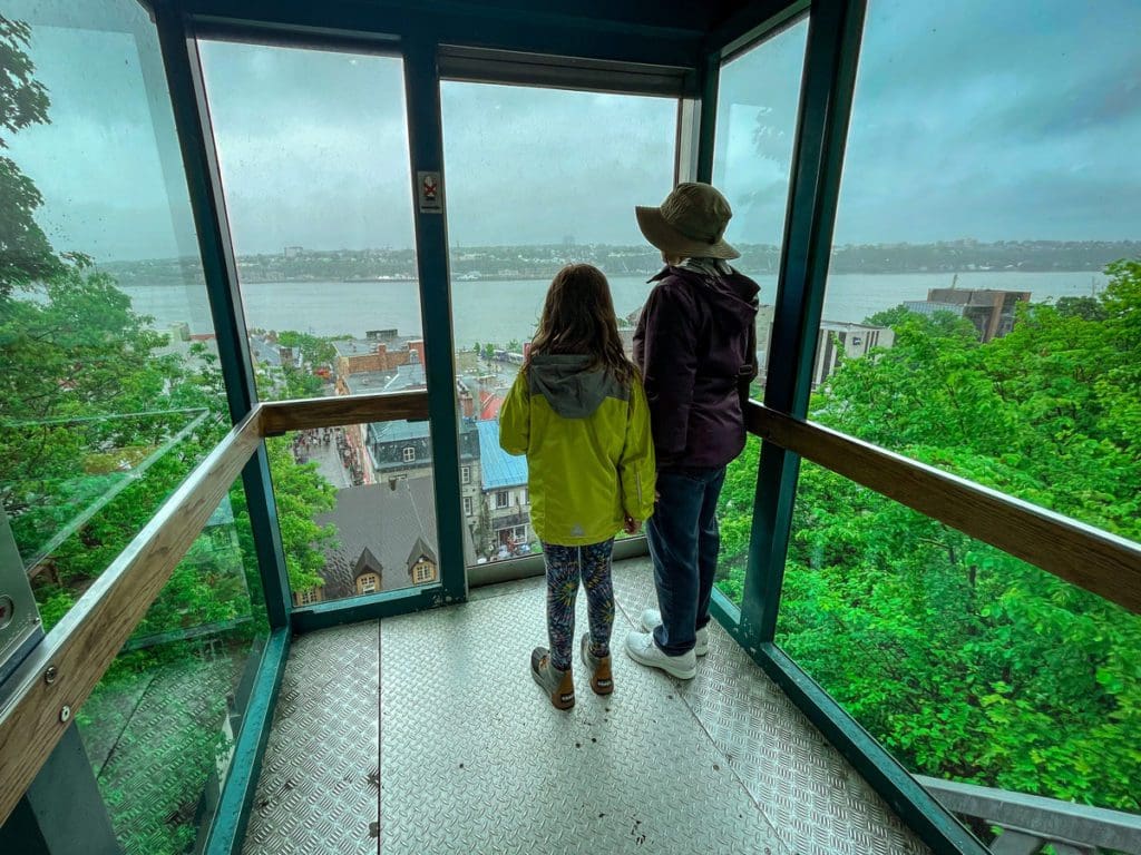 A young girl and her grandmother look out onto a view of the Saint Lawrence River from the funicular in Quebec City, a must do on any Quebec City itinerary with kids.