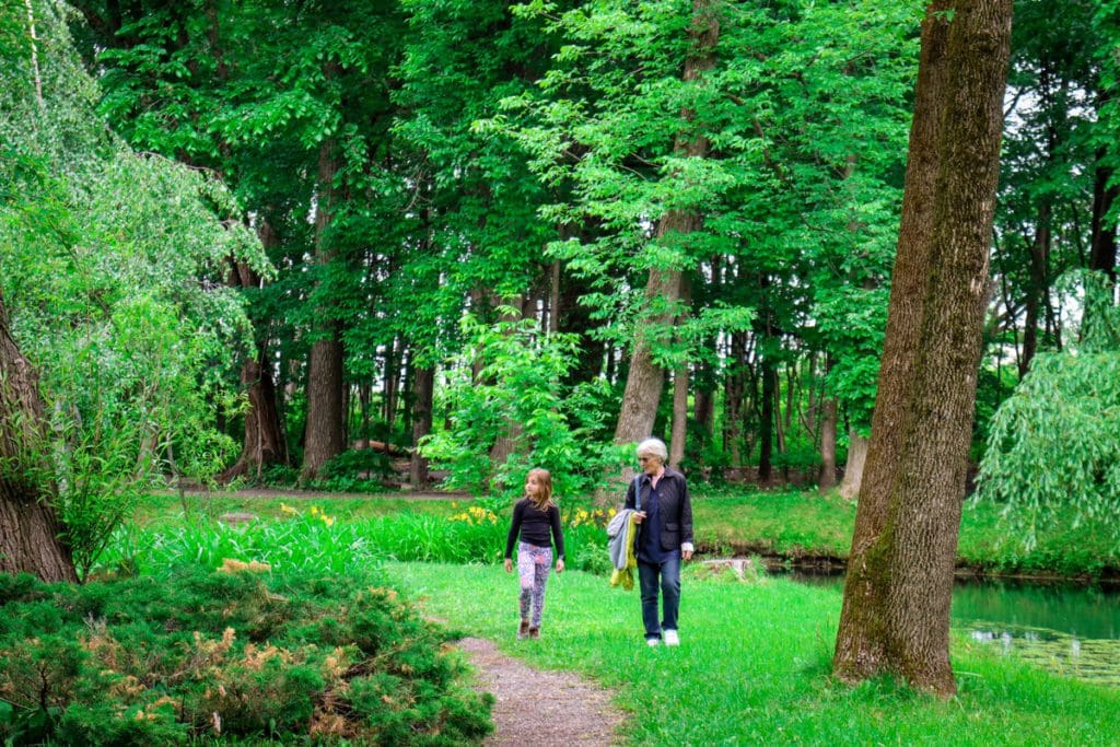 A woman and her granddaughter walk together along a path.