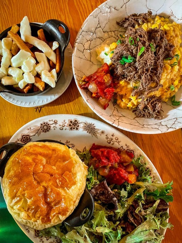 A spread of Quebecois food at Restaurant La Bûche, including Shepard's pie and meat pie, a must eat on any Quebec City itinerary with kids.