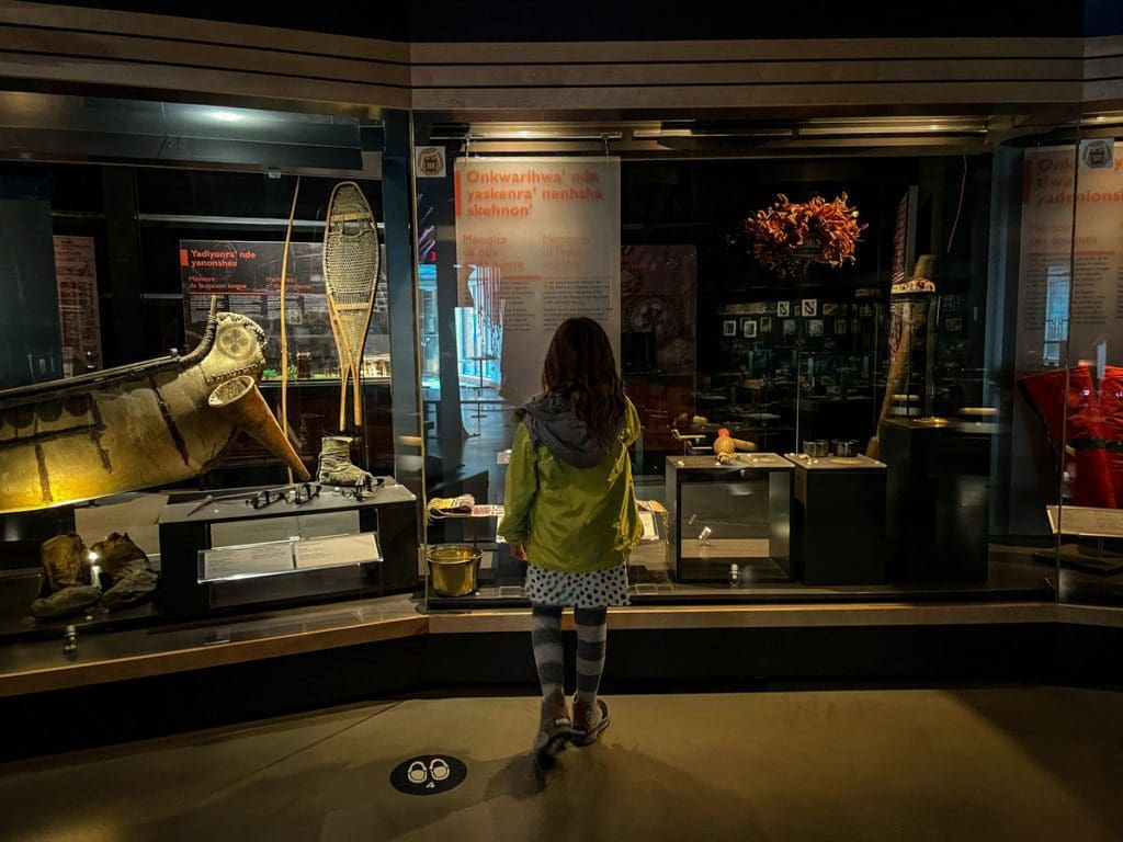 A young girl looks at museum displays inside the Musée Huron-Wendat, a must do on any Quebec City itinerary with kids.