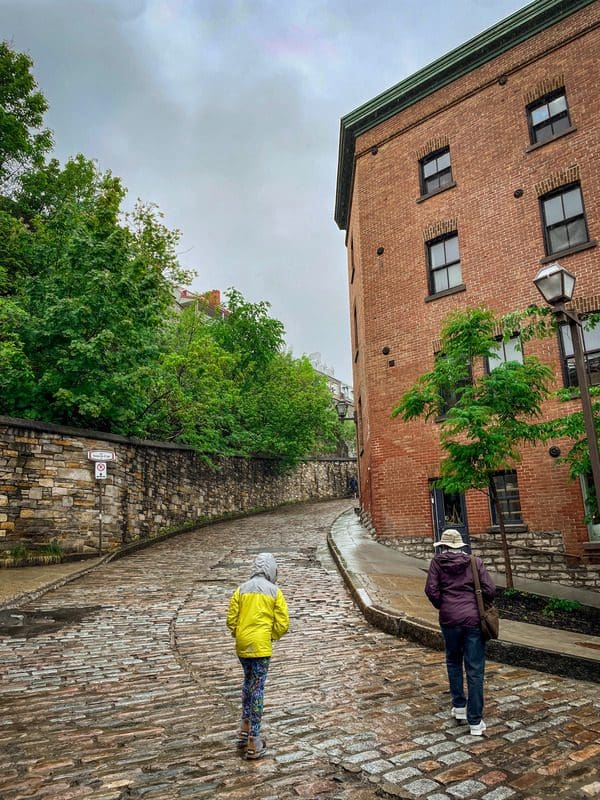 A woman and her granddaughter walk up a steep hill in Quebec City.