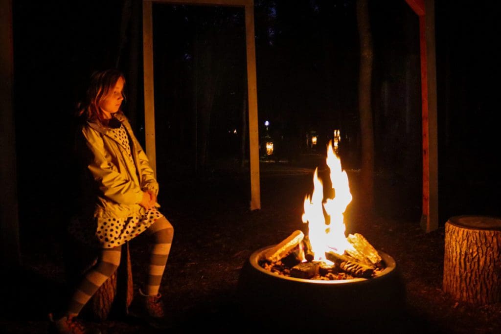 A young girl looks into a bonfire at Onhwa' Lumina.