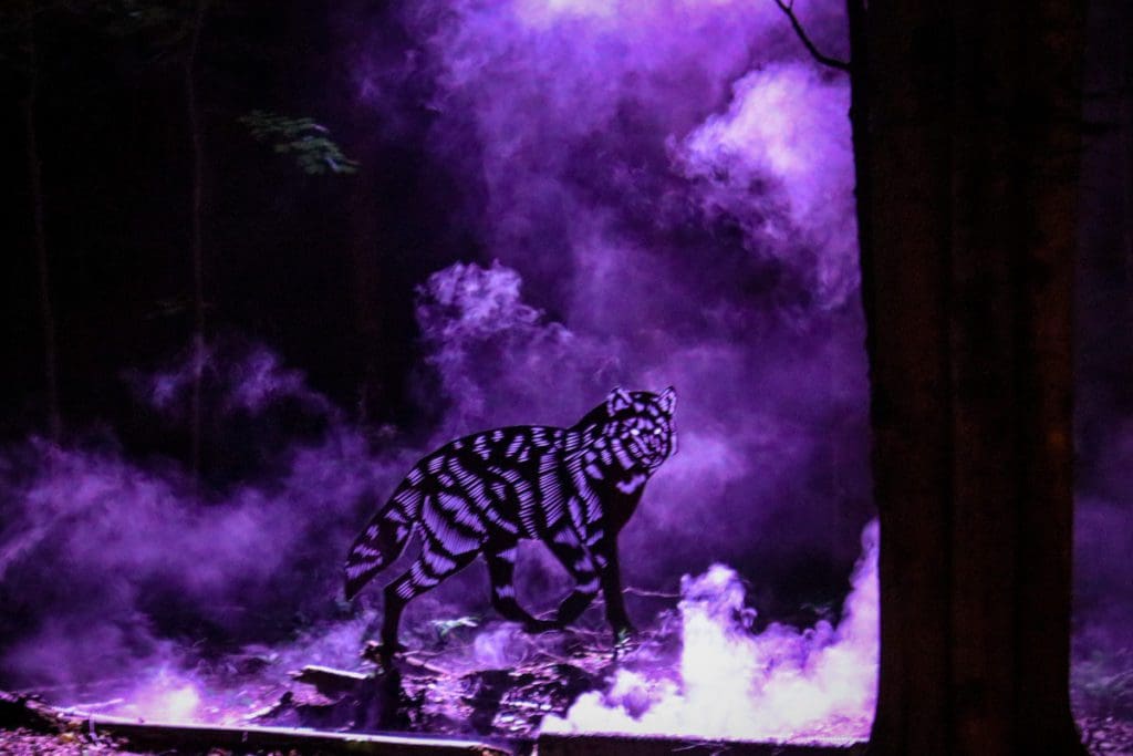 A wolf statue illuminated in fog and purple lights along the path of Onhwa' Lumina.