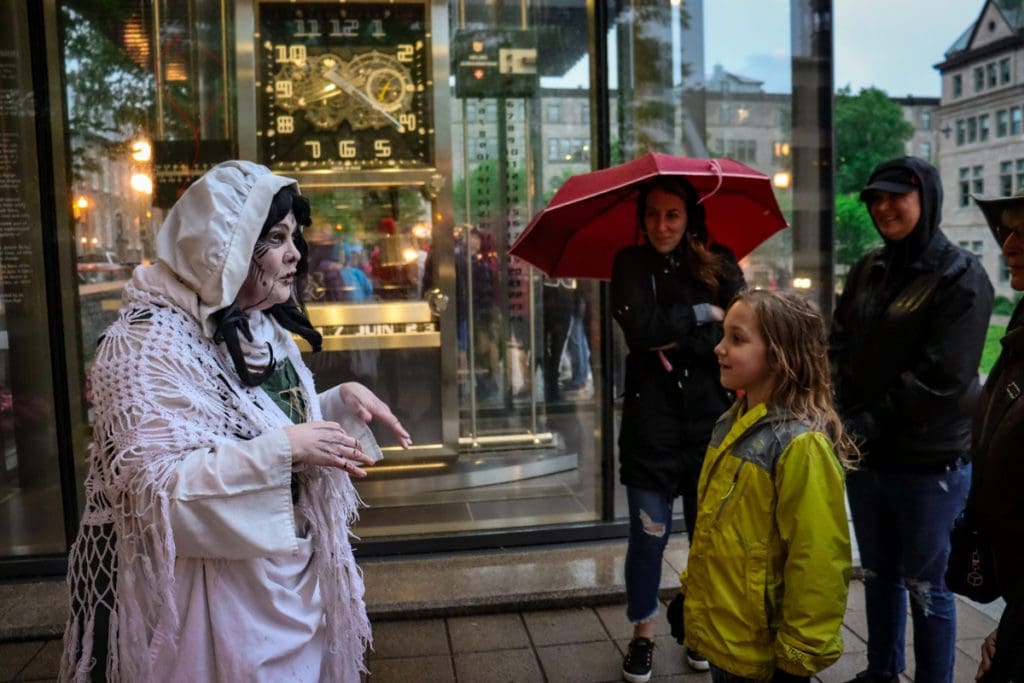 A young girl enjoys the story-telling of a guide on a Les Promenades Fantômes' Walk with Ghosts in Old Quebec, a must do on any Quebec City itinerary with kids.