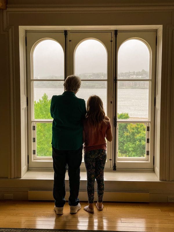 A woman and her granddaughter stand together, looking out onto a view of the Saint Lawrence River from their apartment at Royal Dalhousie.
