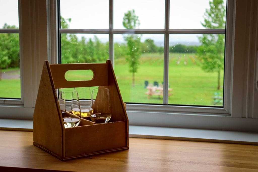 A wine tasting set sits on a table with a view of a vineyard out the window at Sainte-Pétronille's Wineries on Îles d'Orléans.