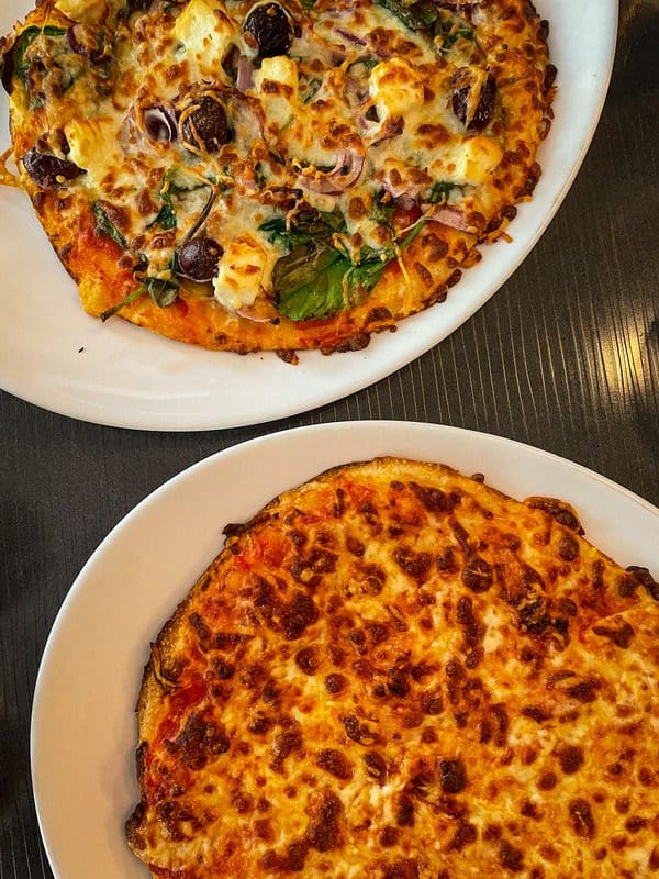 Two pizzas on a table at La Pizz Place Royale, a must eat on any Quebec City itinerary with kids.