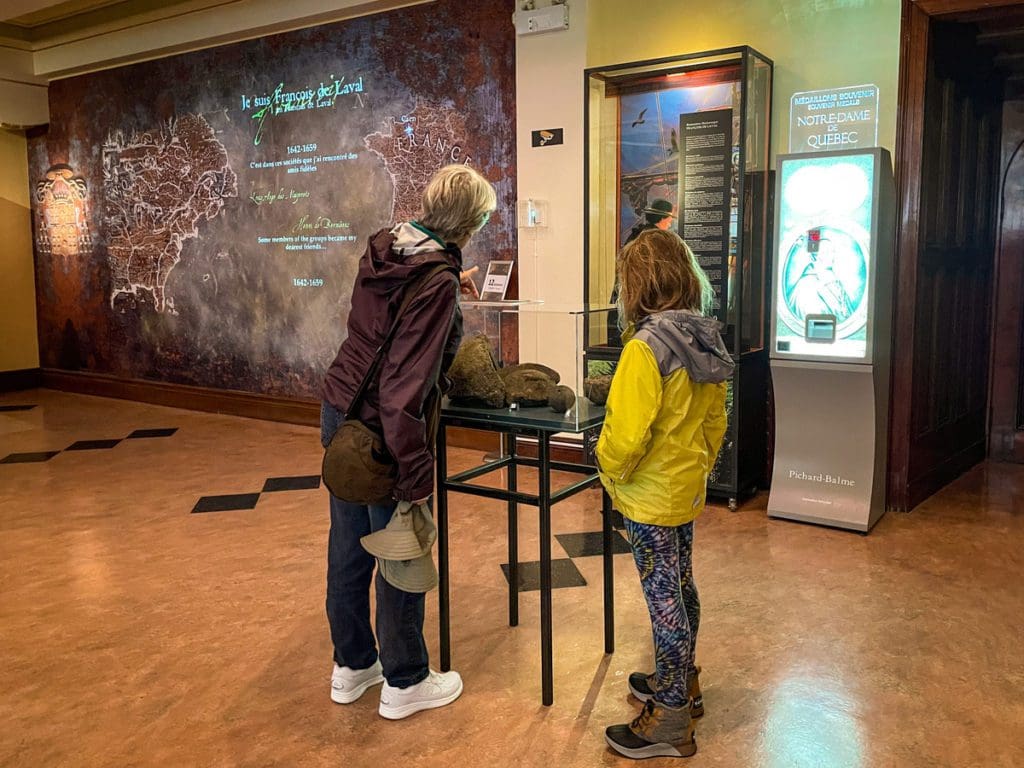 A woman and a young girl read a display in the small museum at Basilique-cathédrale Notre-Dame de Québec, a must do on any Quebec City itinerary with kids.