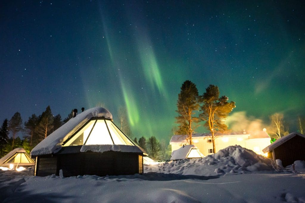 An exterior view of one of the cabins at Apukka Resort, with the northern lights above.