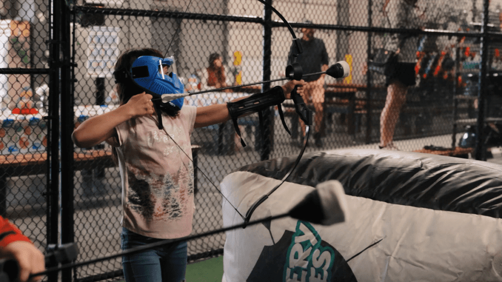 A young girl aims a dodgeball-type arrow during a game at Archery Games Denver.