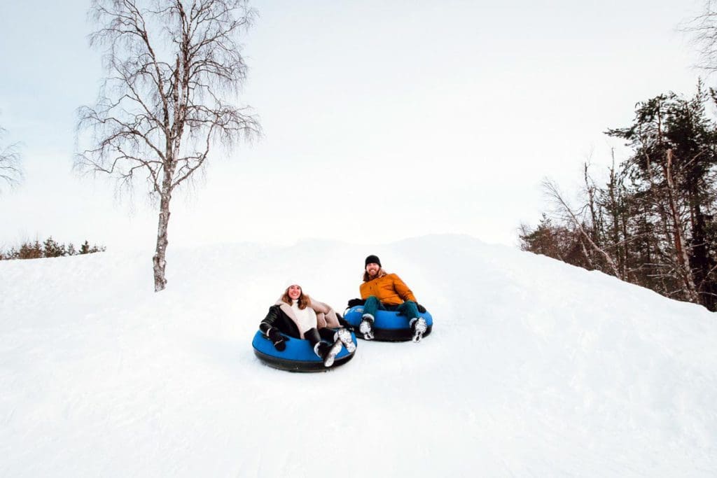 Two people sled down a hill at Arctic SnowHotel & Glass Igloo.