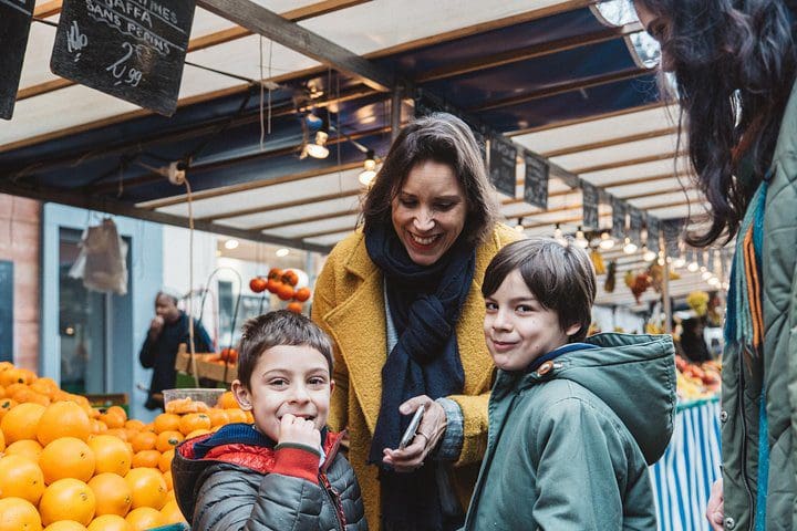 A mom and her two young sons enjoy a market, while on the Paris's Flavors: Customized Food Tour for the Whole Family.