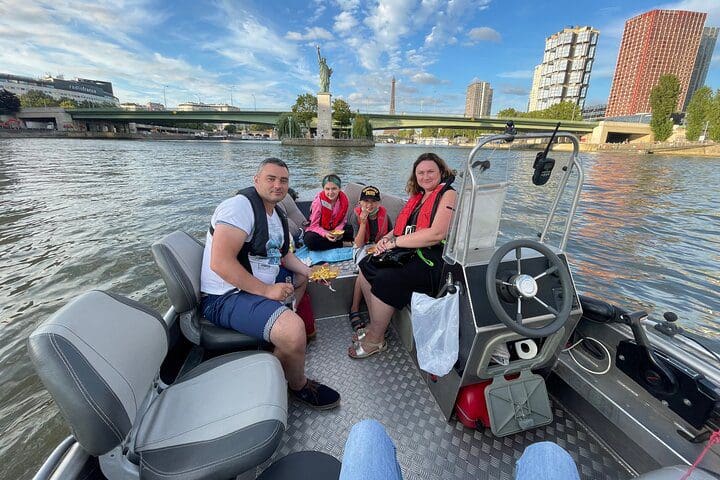 A small family smiles, while sitting on the bow of a boat during a Paris Seine River Private Boat Tour.