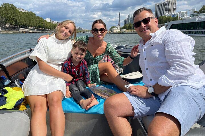 A family poses together on a boat, while enjoying a Paris Seine River Private Boat Tour.