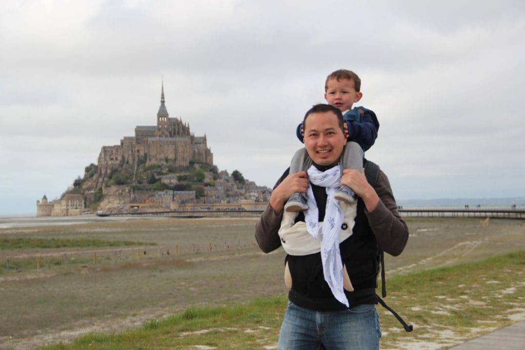 A young boy sits atop his dad's shoulders outside of Mont Saint-Michel.