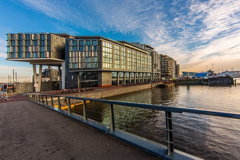 The exterior of Doubletree by Hilton Centraal Station, along a canal in Amsterdam.