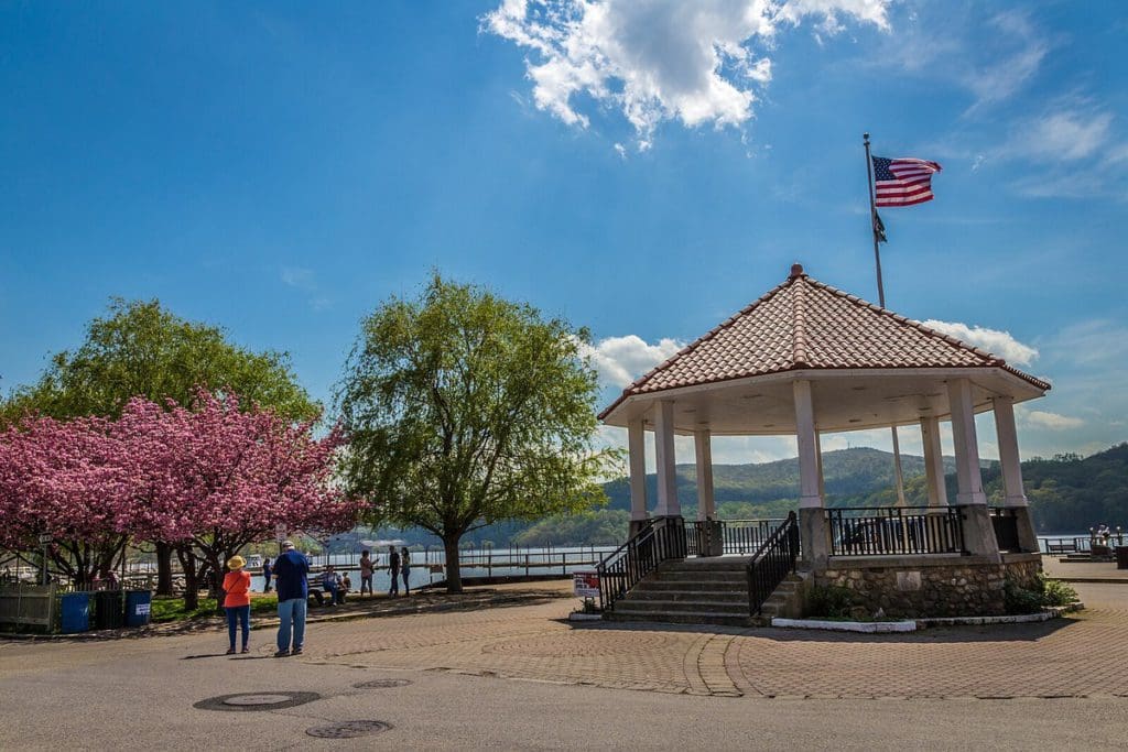 A lovely pavilion along the water, with blooming trees nearby, in Cold Spring, New York, one of the best cute towns near NYC with kids.