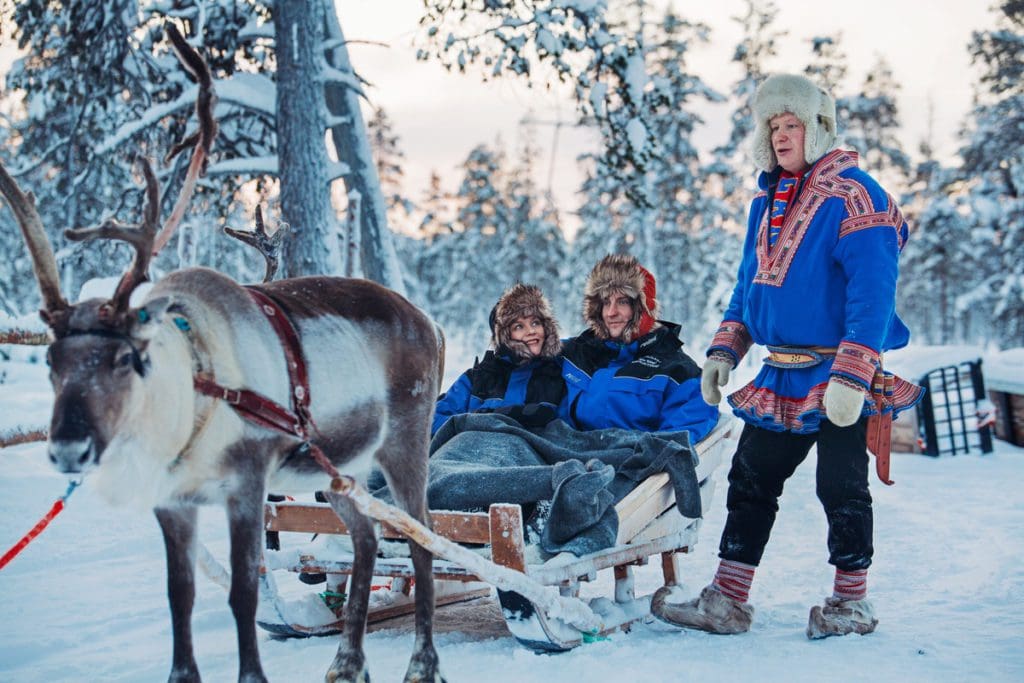 A couple rides a sled pulled by a reindeer at Kakslauttanen Arctic Resort.