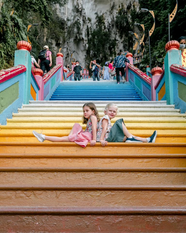 Two kids sit on the colorful steps of the Batu Caves in Malaysia.