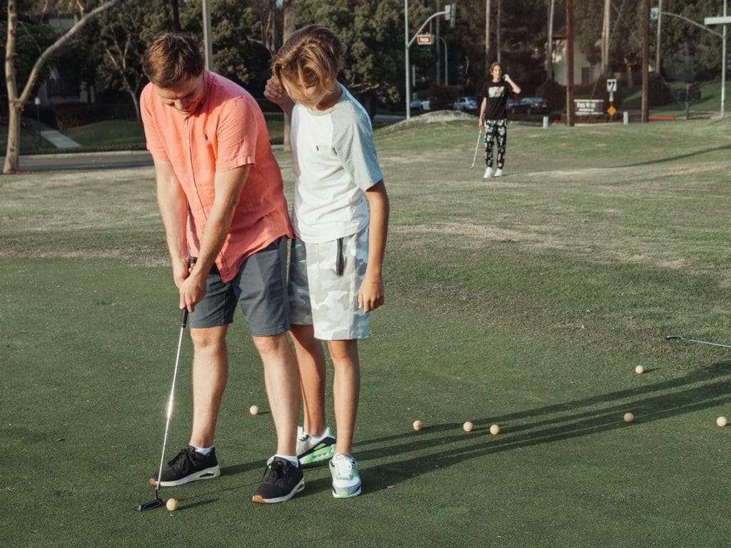 A father and son golf together, one of the top father-son weekend ideas.