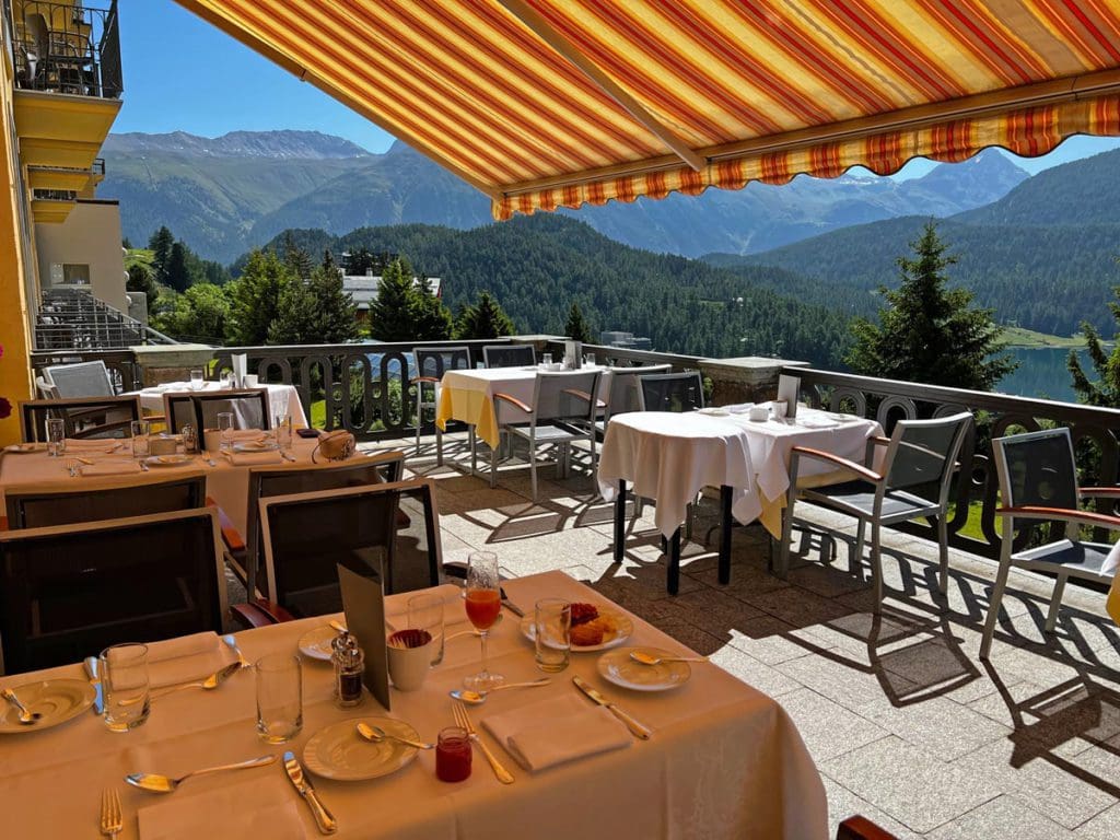 The outdoor breakfast terrace at Kulm Hotel St. Moritz, with a view of the mountains, one of the things you'll learn about in this review.