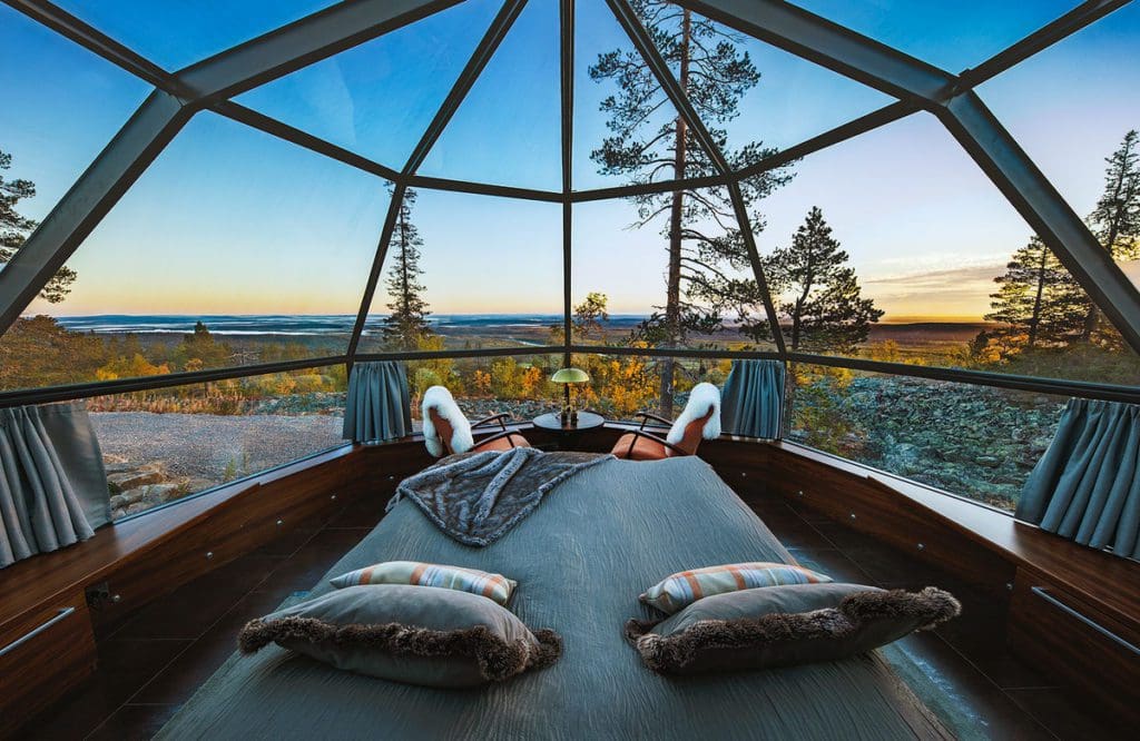 A bed inside one of the igloos at Levin Iglut – Golden Crown, facing the large windows out onto a fall view.