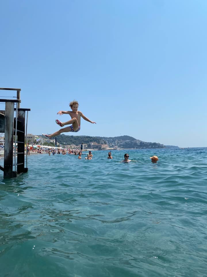 A young boy jumps into the water from a dock in Nice, one of the best places to visit in France with kids.