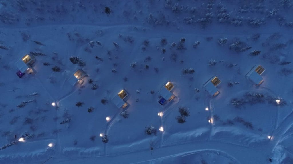 An aerial view of several cabins, lit up at night, at Northern Lights Ranch, one of the best Finland hotels for families.