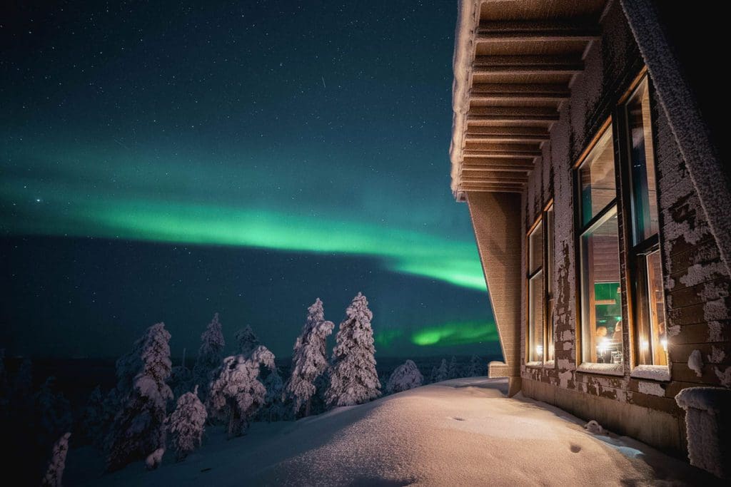 A cabin at OCTOLA, with the northern lights in the distance.