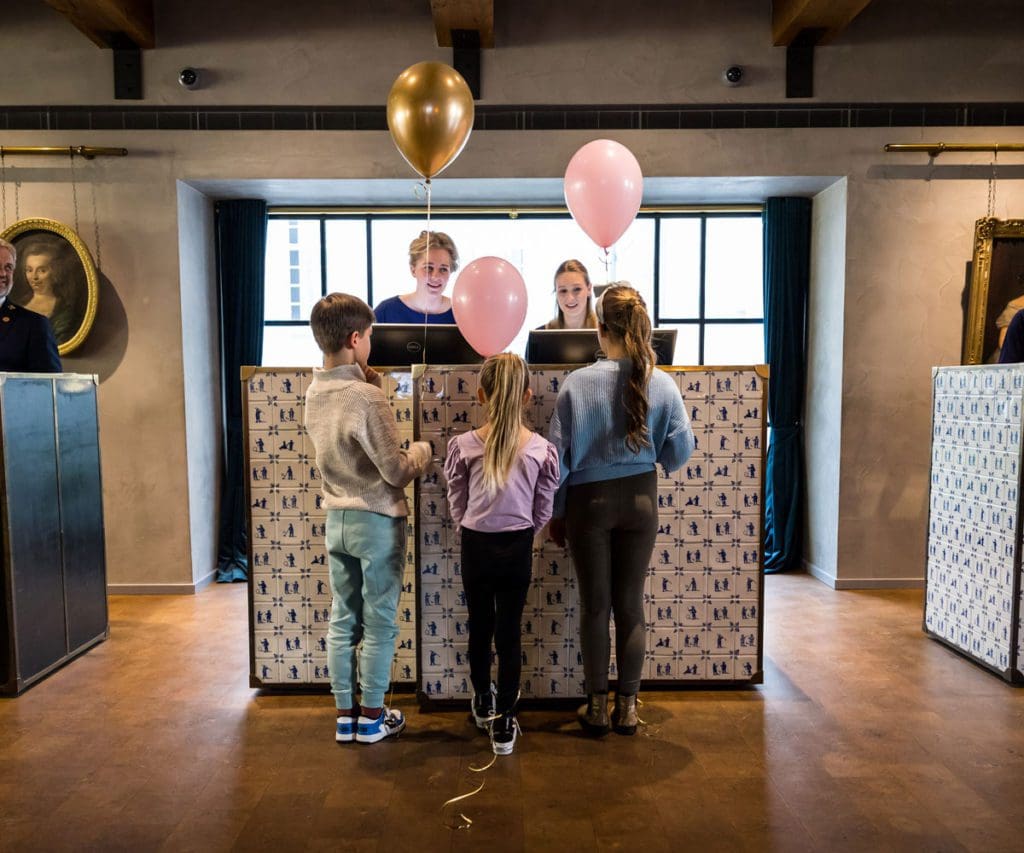 Two kids talk to staff members, while they check into Pulitzer Amsterdam.