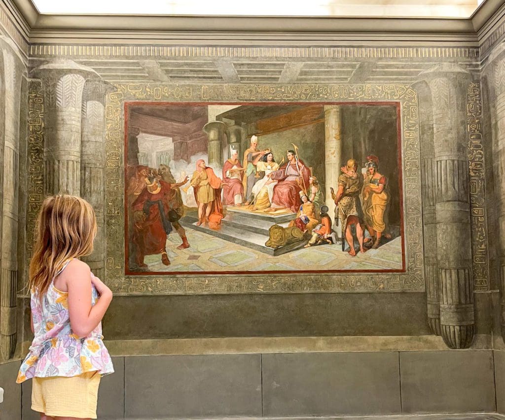 A young girl looks at a painting in a museum in Rome.