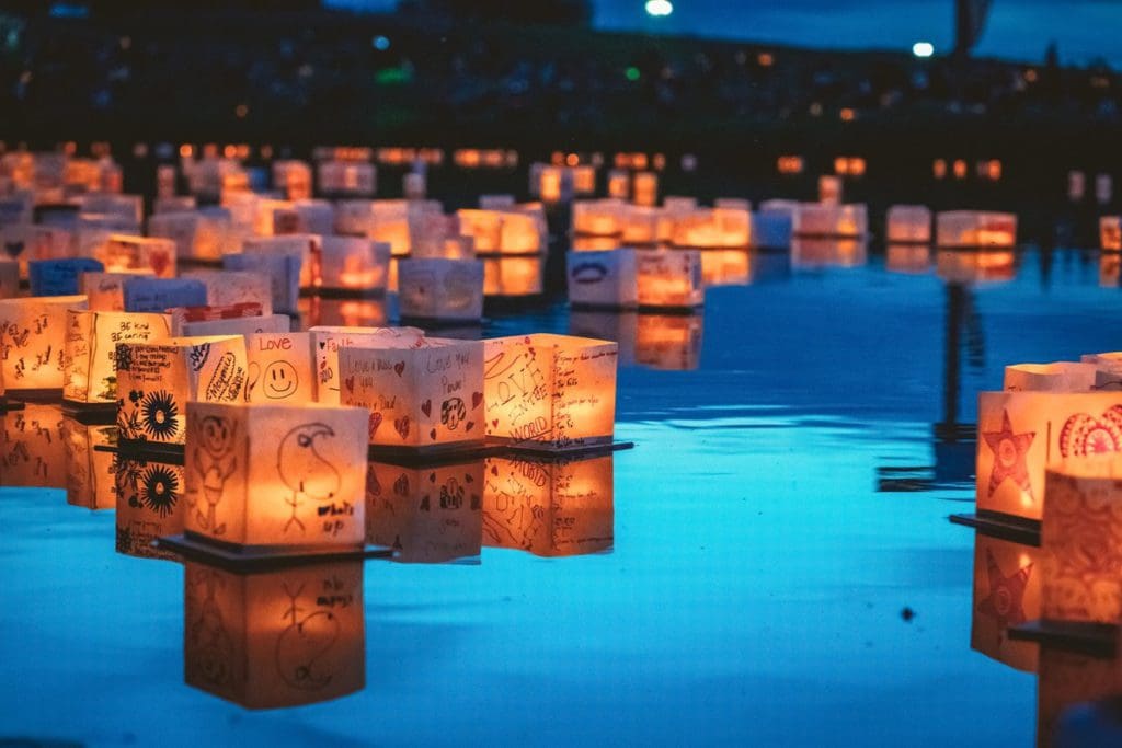 Several lanterns, lit with wishes, float on a pond at the Water Lantern Festival.