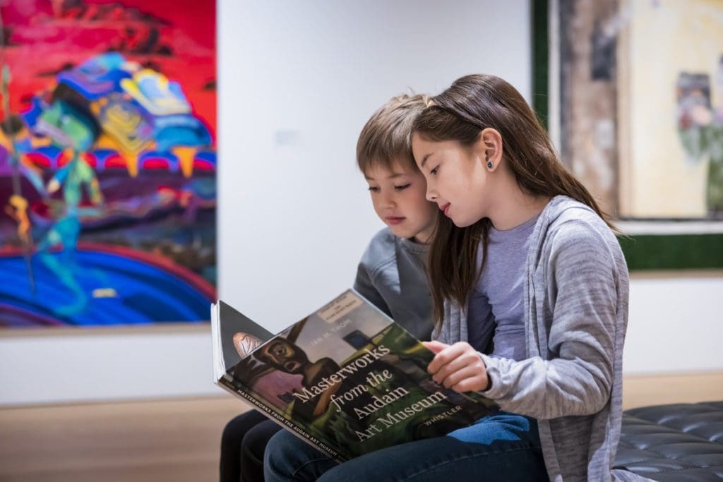 Two kids read a book, while sitting in a gallery at Audain Art Museum, one of the best things to do in Whistler with kids this summer.