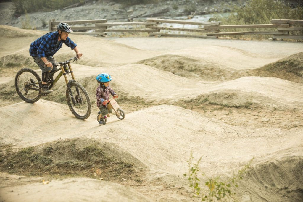 A young boy and his dad bike at a bike park in Whistler.