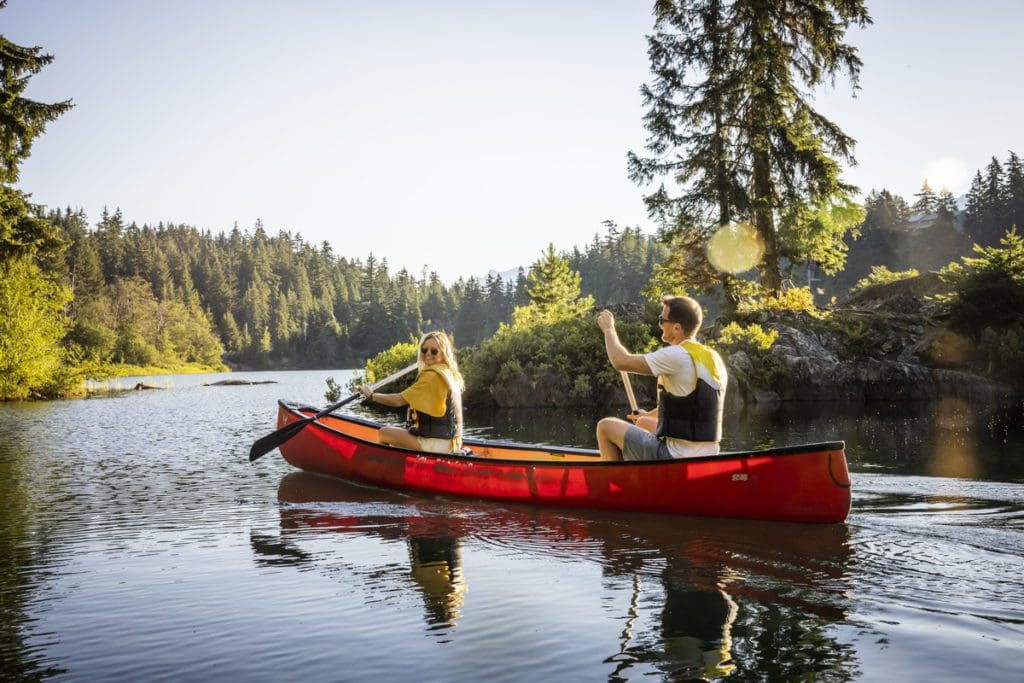 Two people canoe along a serene lake, one of the best things to do in Whistler with kids this summer.
