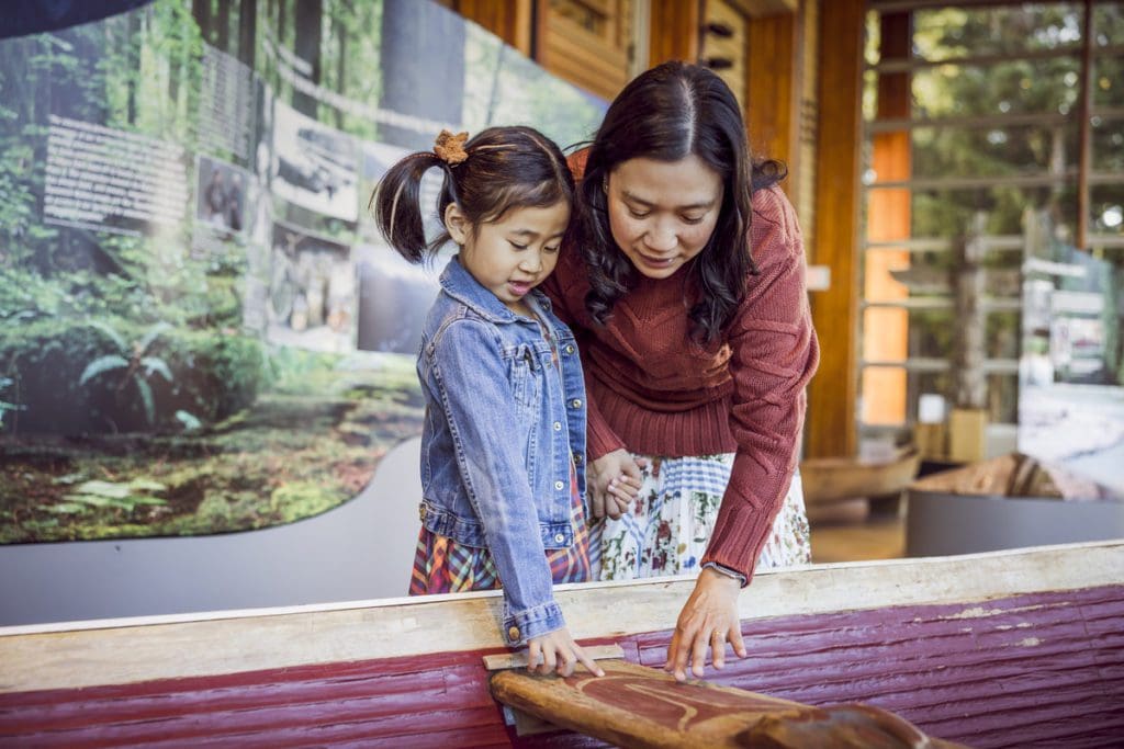 A mom and her young daughter interact with an exhibit at Squamish Lil’wat Cultural Centre, one of the best things to do in Whistler with kids this summer.