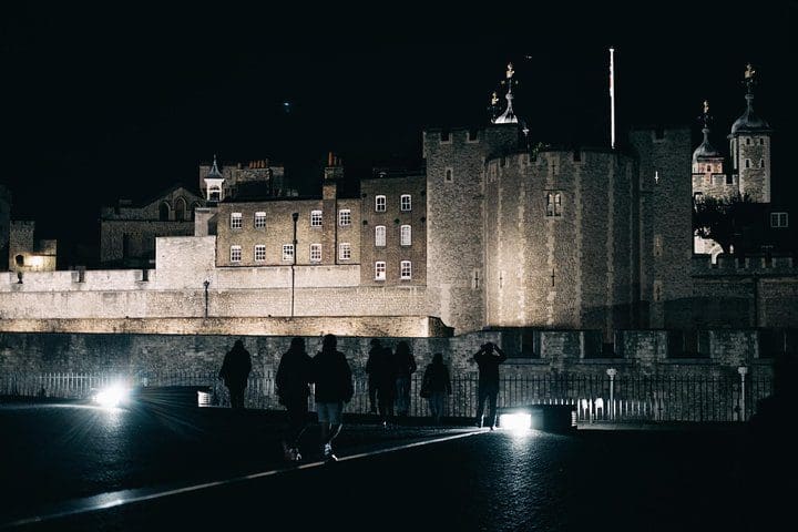 A tour guide leads a group of people on a ghost and ghouls tour of London at night, one of the best experiences in London with kids. 