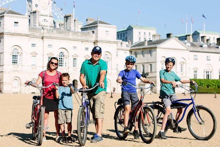 A family of five poses together, while on a bike tour of London, one of the best experiences in London with kids. 